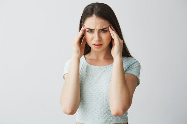 Síndrome del acento extranjero - Mujer joven tocándose la cabeza con gestos de dolor y preocupación