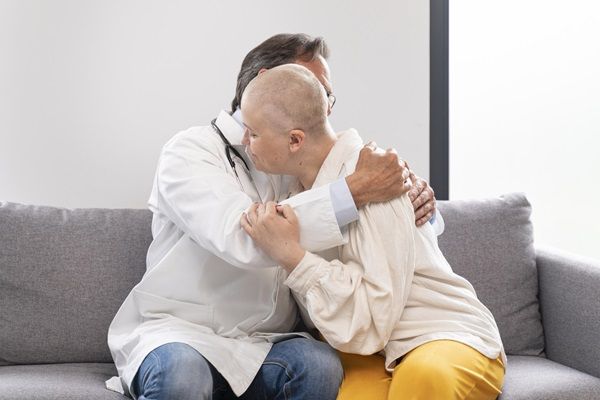 Doctor abrazando a una mujer con la cabeza rapada por el cáncer