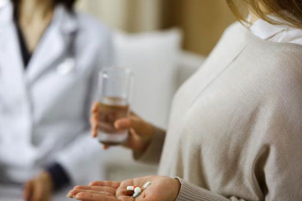 Mujer con pastillas en mano inicia una terapia de sustitución hormonal bajo prescripción médica 