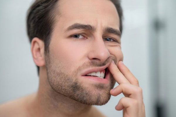 Aftas bucales - Hombre con problemas bucales revisa sus dientes tras experimentar recurrentes molestias en la boca
