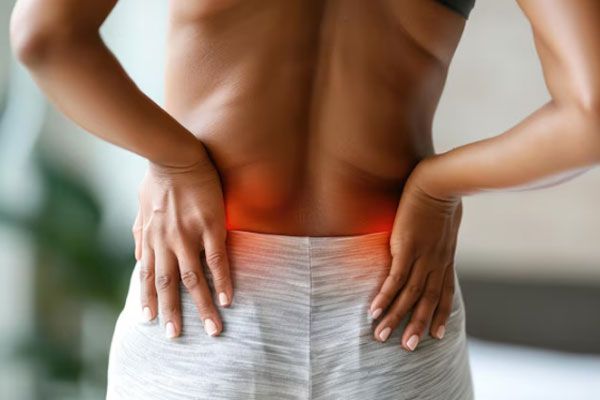 Síndrome de Turner - Mujer con dolor renal lleva sus manos a la parte posterior de su espalda 