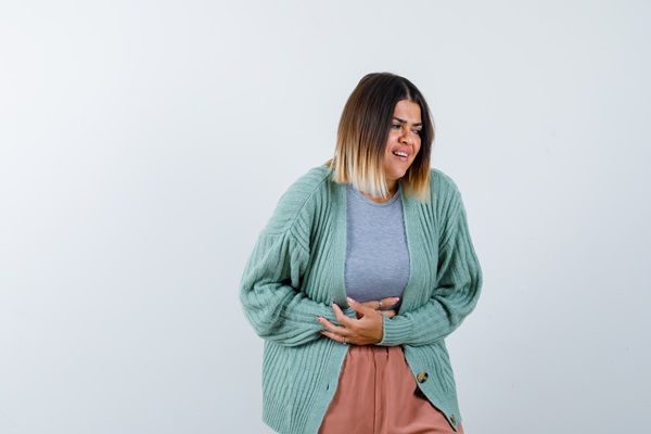 Celiaquía o intolerancia al gluten - Mujer poniendo sus manos sobre el estómago con cara y gestos de dolor