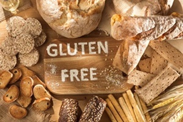 Letrero de gluten free sobre una mesa junto a varios alimentos hechos de harina de trigo y avena