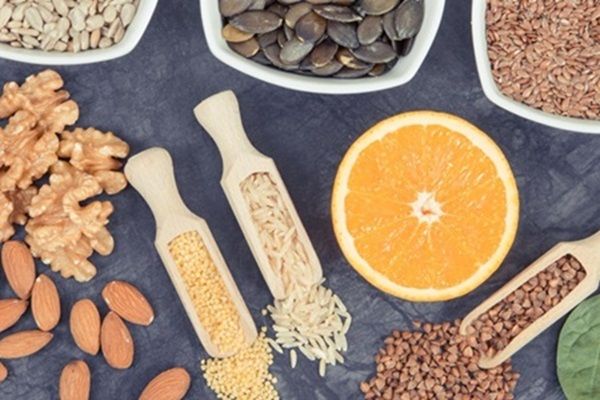 Enfermedad de Graves tratamiento natural - Granos de arroz, nueces, almendras y semillas junto a media naranja sobre una mesa