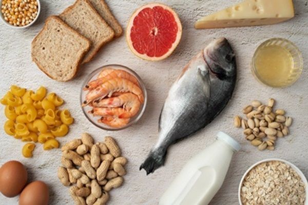 Enfermedad de Graves tratamiento natural - Diversos alimentos como pescado, camarones, maíz, almendras, pan, leche y queso sobre una mesa blanca