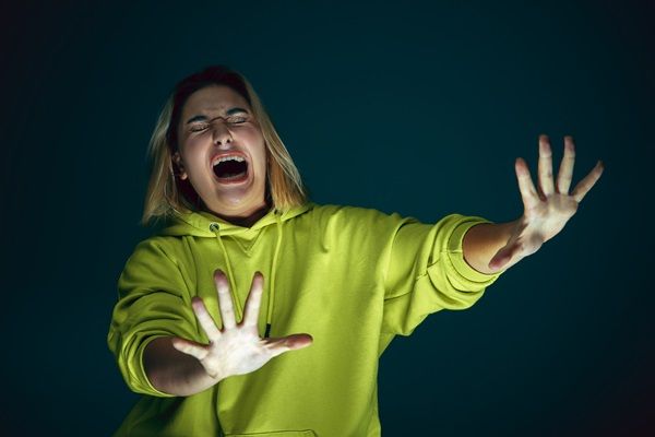 Síndrome de Cotard - Mujer con los ojos cerrados y cara de terror extendiendo sus manos abiertas con mucho miedo
