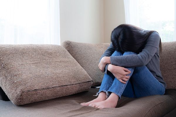 Síndrome de Cotard - Mujer con depresión sentada cabizbaja sobre el mueble