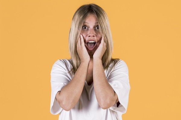 Síndrome de Cotard - Mujer joven tocándose el rostro con las manos mientras pone cara de sorprendida