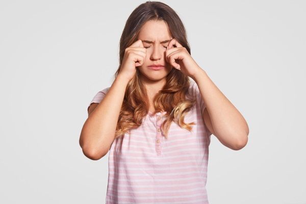Síndrome de Sjögren - Mujer joven restregando sus ojos para aliviar las molestias que causa la enfermedad de las glándulas lagrimales