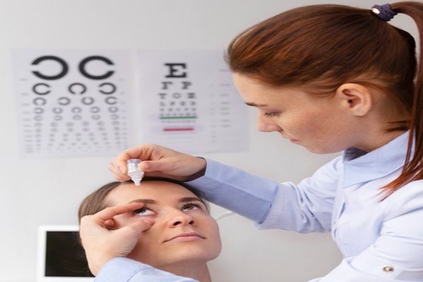 Oftalmóloga aplicando unas gotas en los ojos de una paciente femenina para aliviar la irritación