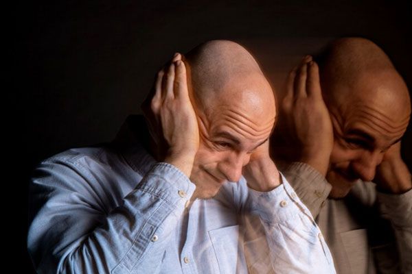 Esquizofrenia paranoide - Hombre con alucinaciones auditivas se tapa los oídos para no escuchar las voces de su cabeza 