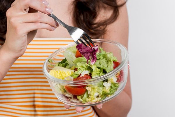 Mujer sujetando un recipiente de cristal con frutas y vegetales para comer una dieta saludable