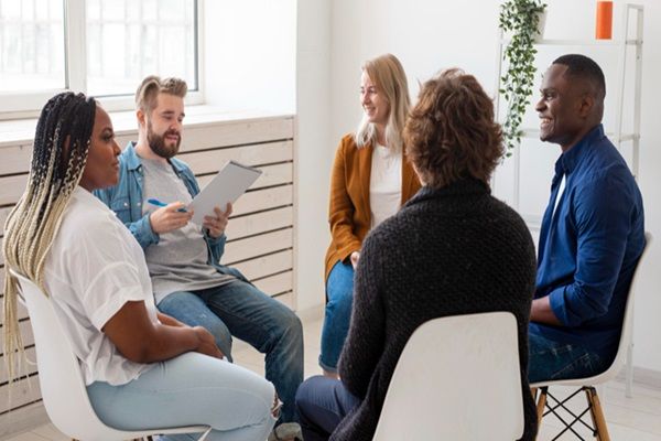 Grupo de personas conversando sentadas mientras se ven de frente en una terapia grupal