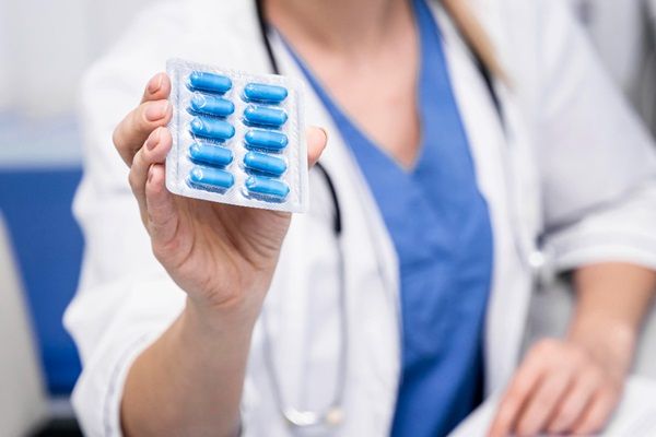 Espondilitis anquilosante esperanza de vida - Doctora sosteniendo en sus manos un empaque de pastillas azules