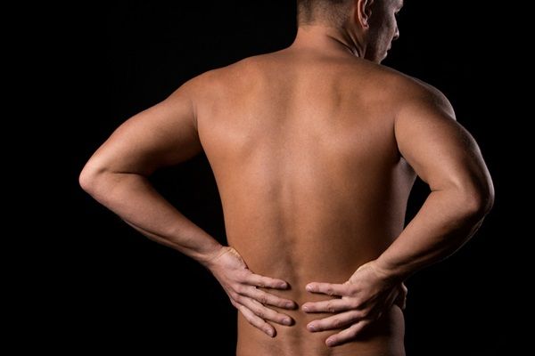 Hombre poniéndose las manos en la espalda baja sobre la columna vertebral