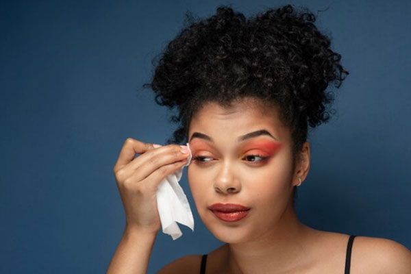 Blefaritis - Joven se desmaquilla los ojos con suavidad para evitar orzuelos y afecciones oculares