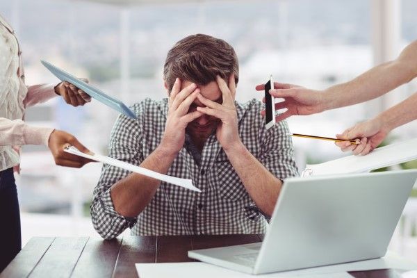 hombre en la oficina agobiado por la gran cantidad de estímulos del trabajo