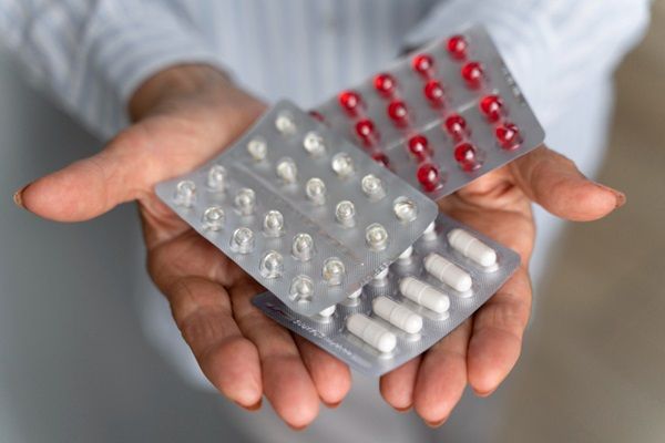 Persona sosteniendo en sus manos varios empaques de pastillas y medicamentos