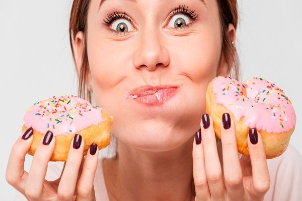 mujer comiéndose unas donas, algo malo para su salud dental