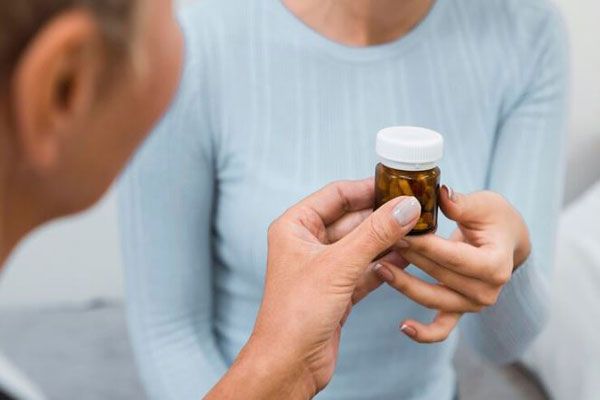 Doctora prescribe un frasco de medicamentos para combatir la ansiedad a una mujer adulta