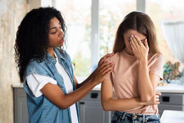 Autolesión - Mujer joven escucha y consuela a un amiga triste y preocupada