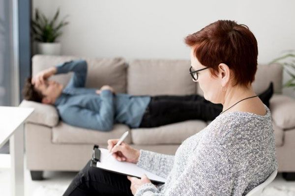 Psicóloga toma nota de los pensamientos de un hombre con problemas de salud mental