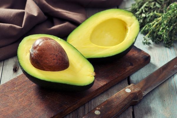 Alimentos que bajan el colesterol - aguacate, un alimento para bajar el colesterol, partido por la mitad sobre una mesa