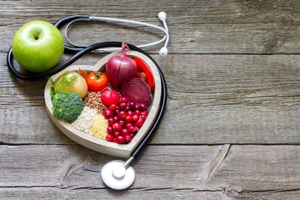 Alimentos que bajan el colesterol - alimentos que ayudan a bajar el colesterol dentro de una bandeja en forma de corazón al lado de un estetoscopio