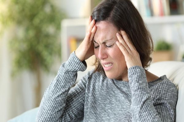 Síntomas de la nueva variante del COVID EG.5 - mujer con fuertes dolores de cabeza uno de los síntomas de la nueva variante del COVID EG.5