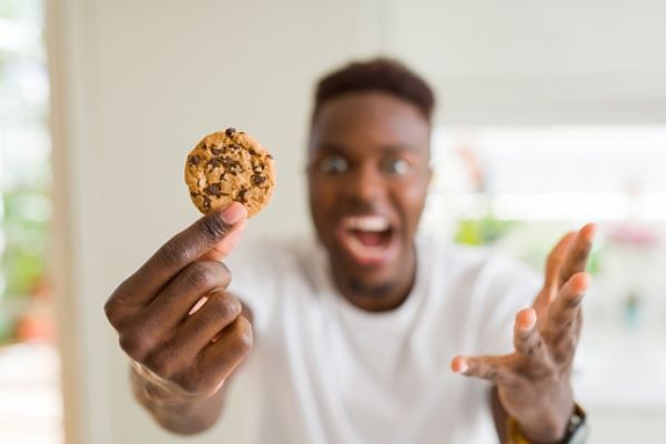 hombre mostrando una galleta realizada en una fabrica, un alimento ultraprocesado más