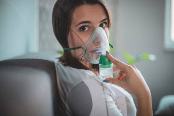 mujer con un nebulizador para poder respirar por los problemas que le produce Eris