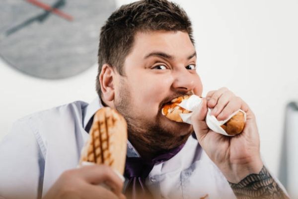 hombre obeso comiendo ansiosamente por culpa del estrés