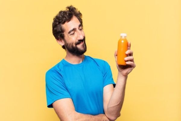 alimentos ultraprocesados - hombre sonriente mirando un jugo envasado otro tipo de alimento ultraprocesado