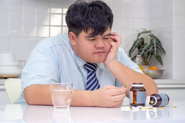 hombre mirando un medicamento que le esta haciendo ganar peso