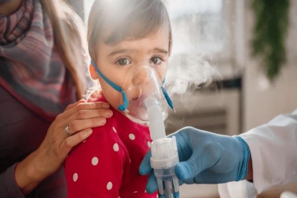 Bronquitis sin fiebre - infante en la consulta del pediatra con un respirador