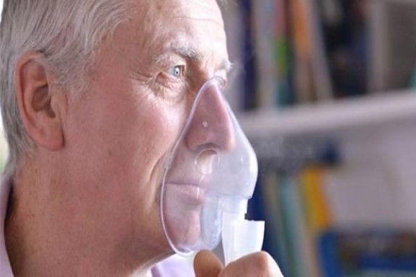 anciano respirando con un nebulizador para mejorar su respiración