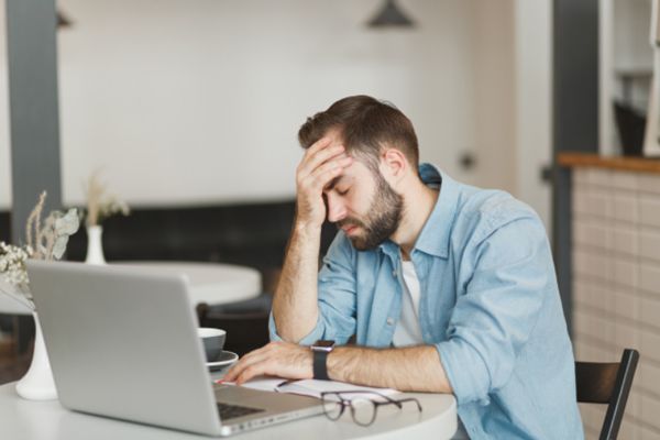 Hombre con estres frente a la computadora. Esto puede causar insufucuencia cardiaca.