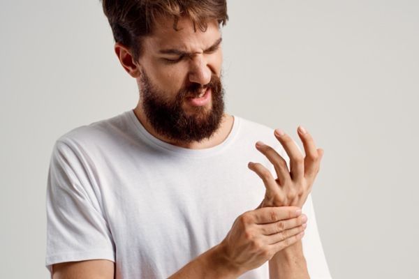 Fractura del escafoides - hombre agarrándose la muñeca con cara de dolor