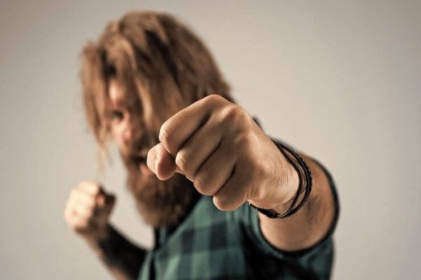 Fractura del escafoides - hombre barbudo lanzando un puñetazo en una pelea callejera