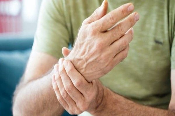 Fractura del escafoides - hombre sentado en el sofá agarrándose la muñeca por el dolor