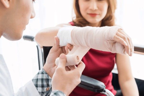especialista vendando el brazo y la mano de una paciente por daños en la muñeca
