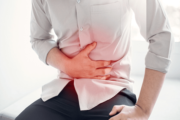 Problemas intestinales – Hombre sentado tocándose el abdomen sufriendo de dolor estomacal 