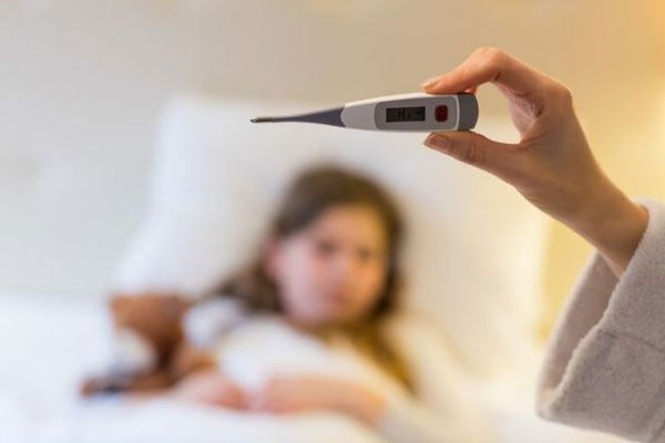 Cómo bajar la fiebre -Mujer mirando el termómetro para comprobar si el cuadro febril de su hija ha bajado