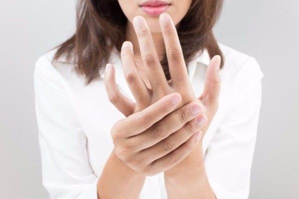 Mujer sujetándose la mano por problemas para mover los dedos por estar rígidos