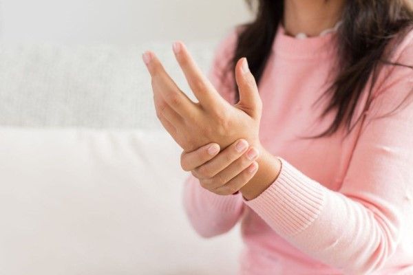 Metacarpianos y falanges - mujer agarrándose la mano por una posible fractura de los metacarpianos y falanges