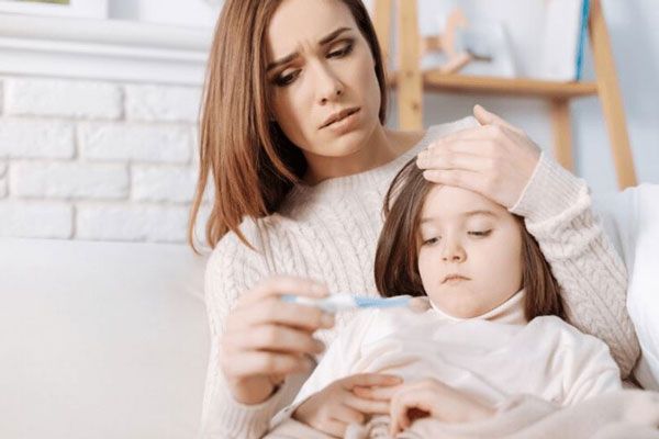 Cómo bajar la fiebre - Madre preocupada usa un termómetro digital para controlar la fiebre de su hija