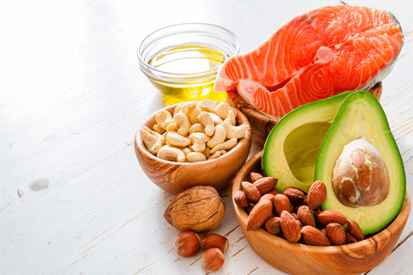 Colesterol bueno y malo - Platos con salmón, aguacate, frutos secos y aceite, alimentos ideales para incorporar grasas saludables y mejorar el equilibrio entre colesterol bueno y malo