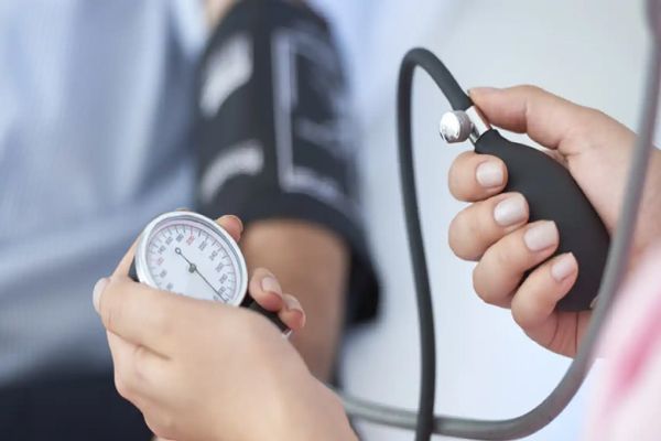 Factores de riesgo cardiovascular- Médico tomando la presión arterial a paciente que presenta sintomas de enfermedad cardiovascular