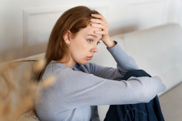 Somatizar enfermedades- Chica joven con trastorno mental recostada en un sofá