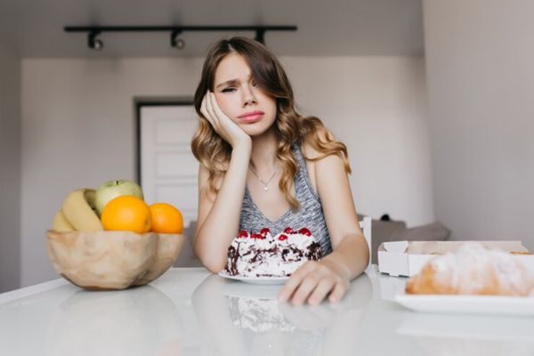 Bulimia nerviosa- Chica con baja autoestima frente a un pastel completo